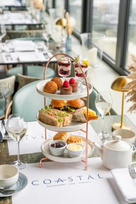 Three-tier afternoon tea stand with sandwiches, scones and desserts at Coastal Restaurant Brighton.