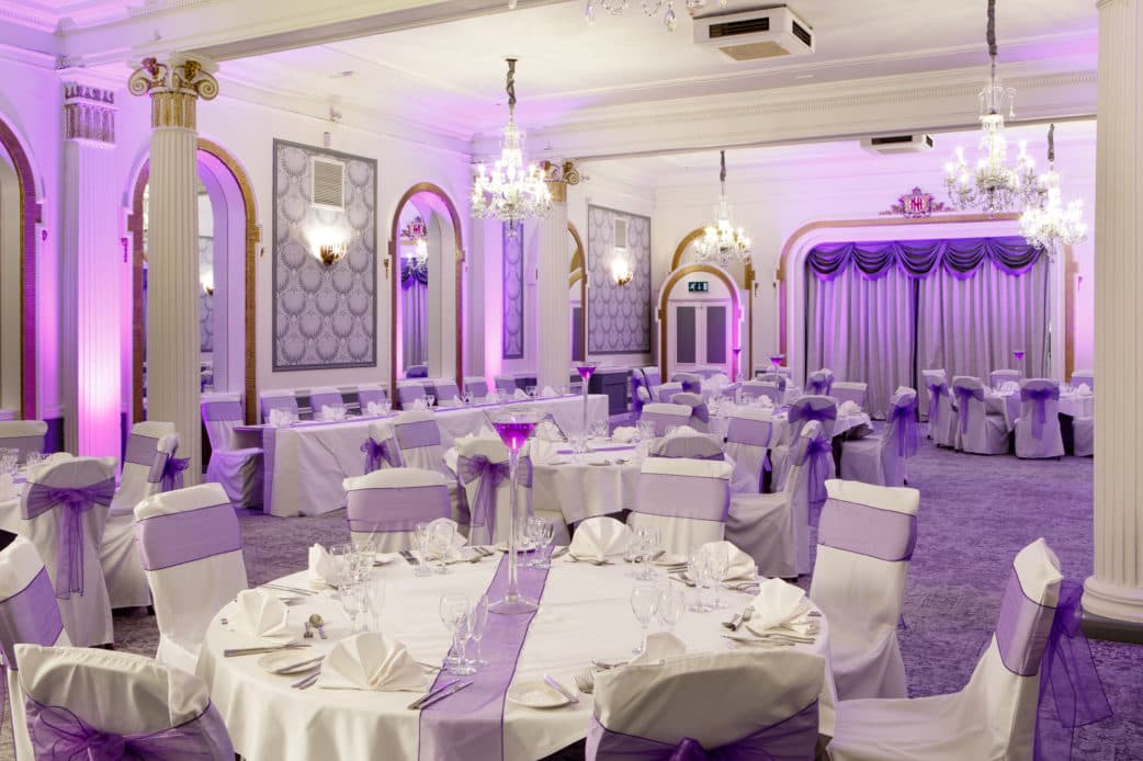 Grand ballroom at Mercure Hotel Brighton Seafront laid for a banquet with purple lighting.