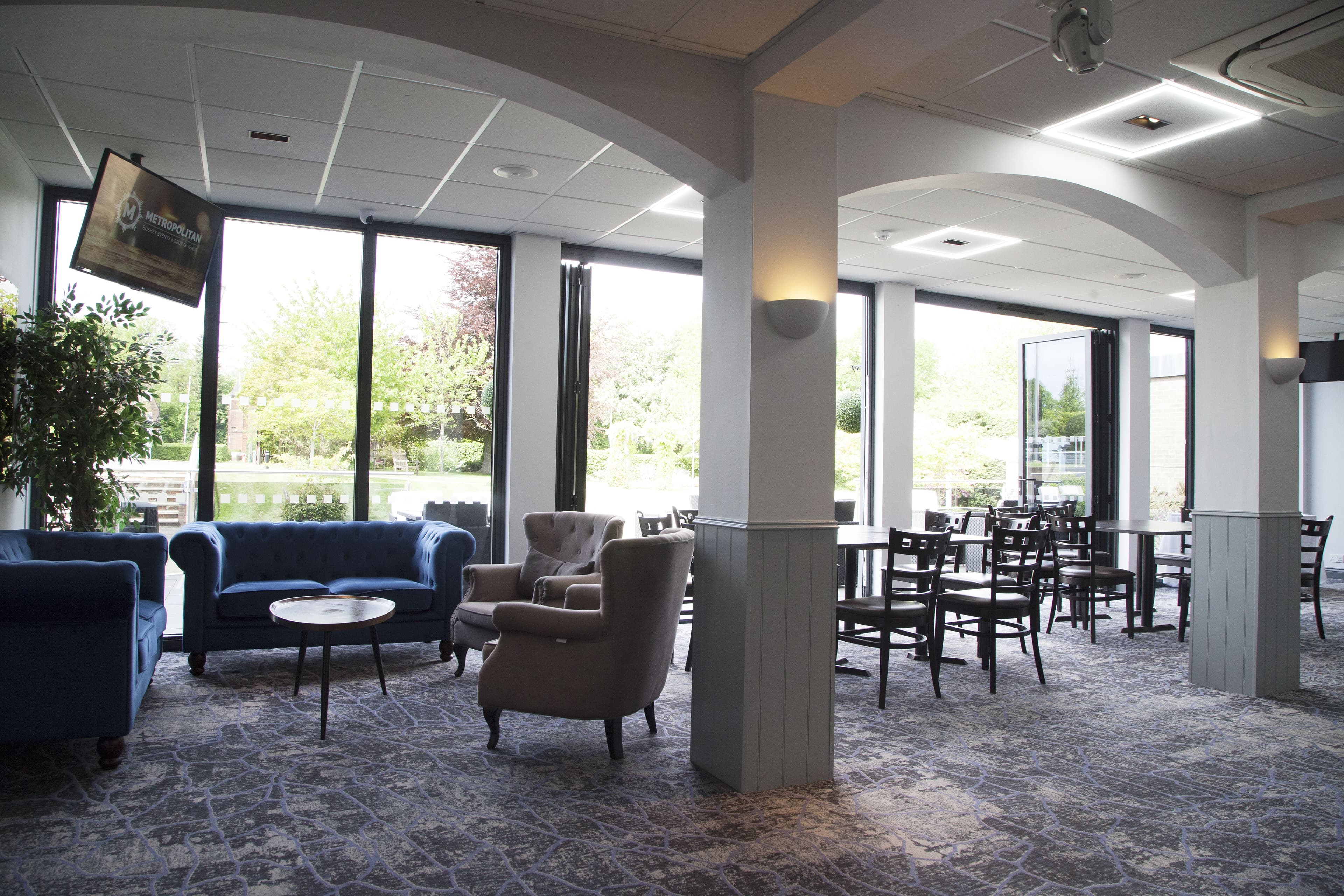 Bright lounge area with blue Chesterfield sofas, wingback chairs and garden views.