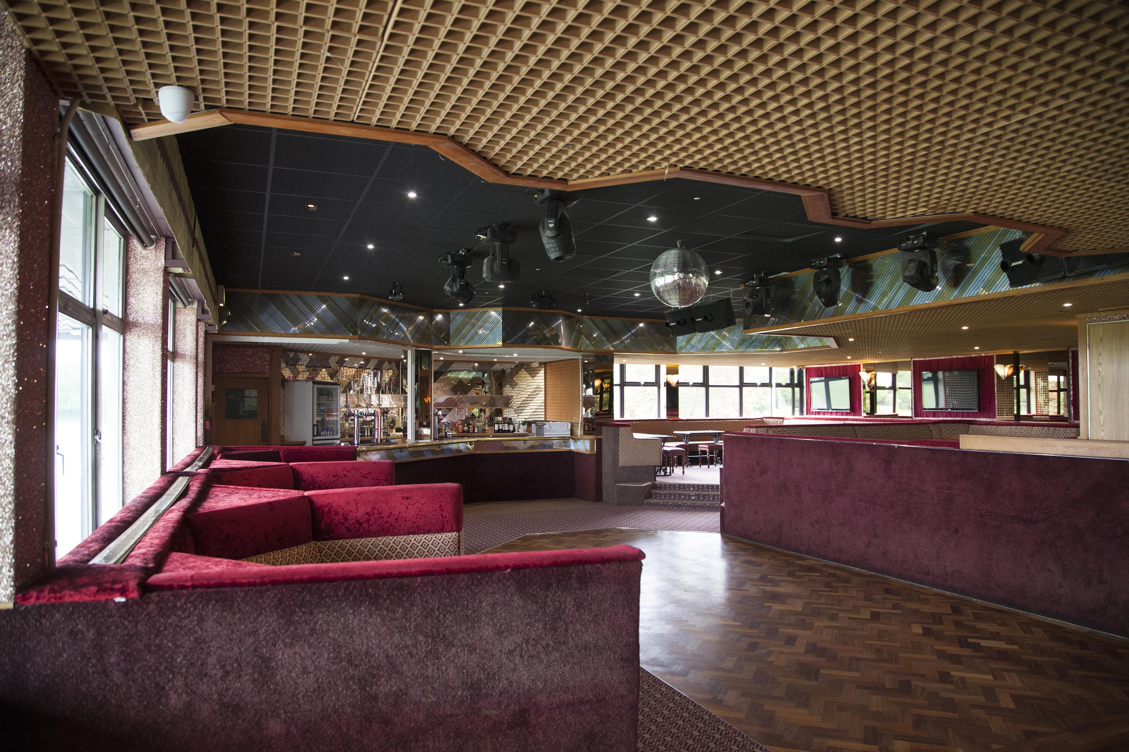 Empty function room with red banquette seating, parquet dancefloor and a mirrored disco ball.