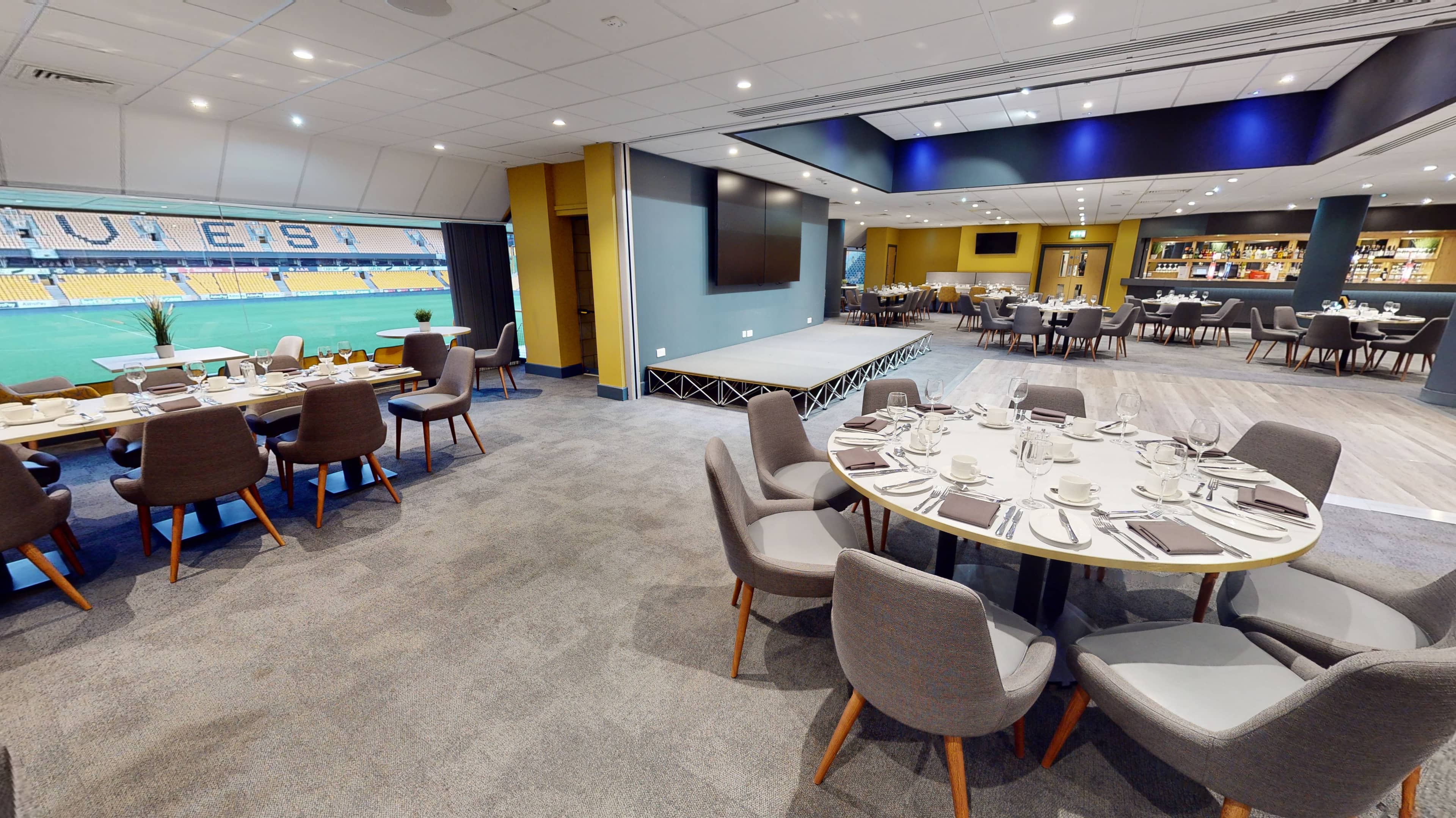 Hospitality suite with round dining tables overlooking the Molineux Stadium pitch.