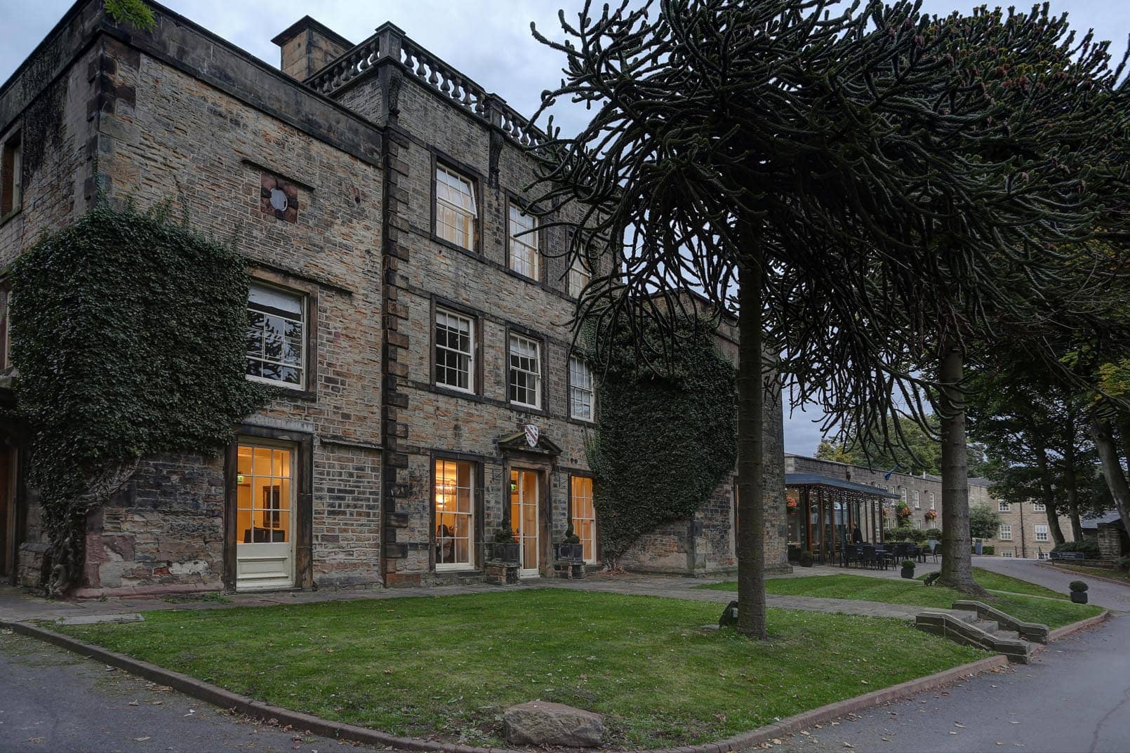 Stone exterior of Mosborough Hall Hotel with monkey puzzle trees and a lawn.