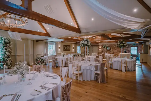Dressed wedding reception room with round tables, chiavari chairs and exposed timber beams