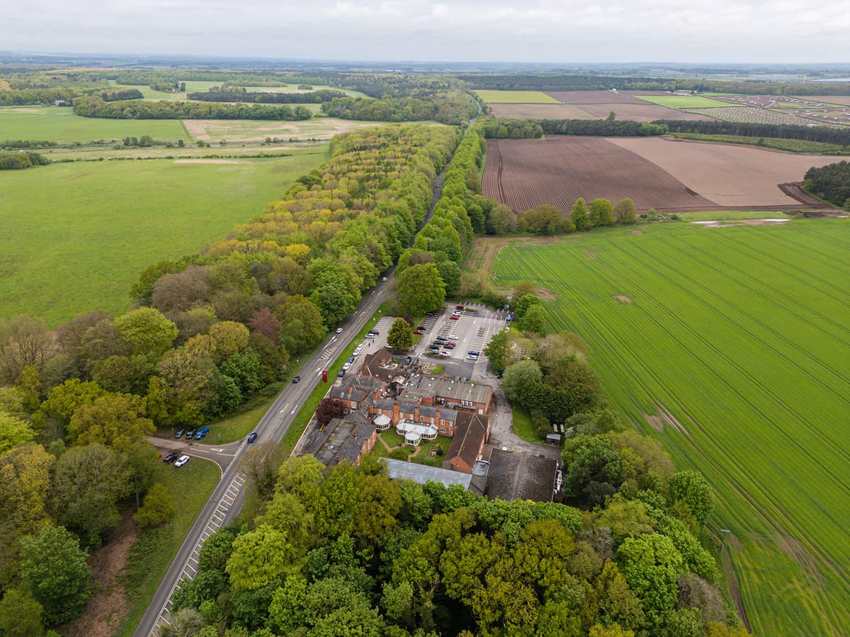Aerial view of Muthu Clumber Park Hotel surrounded by woodland and open farmland.