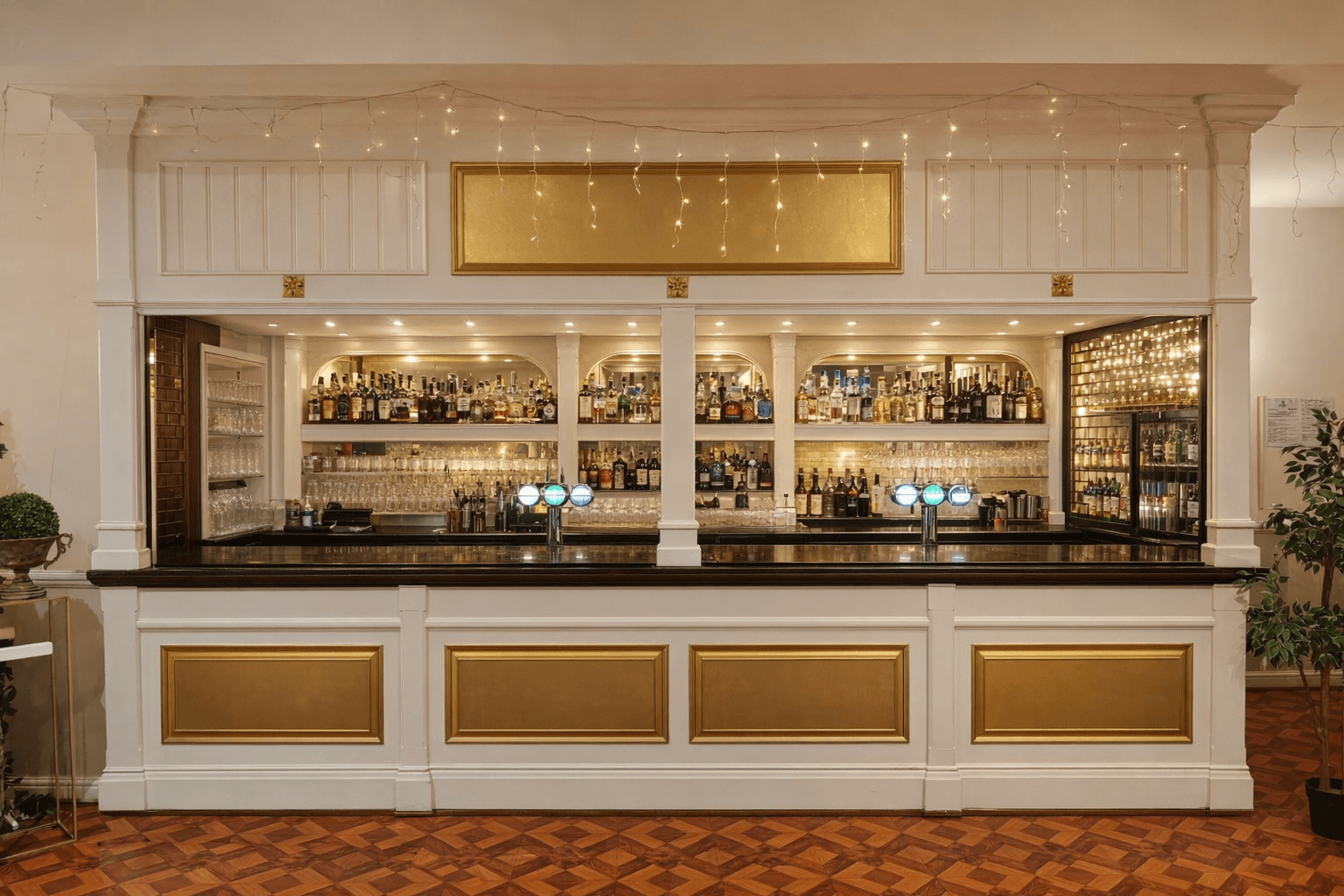 White and gold bar with draped fairy lights, spirit shelves and draught taps.