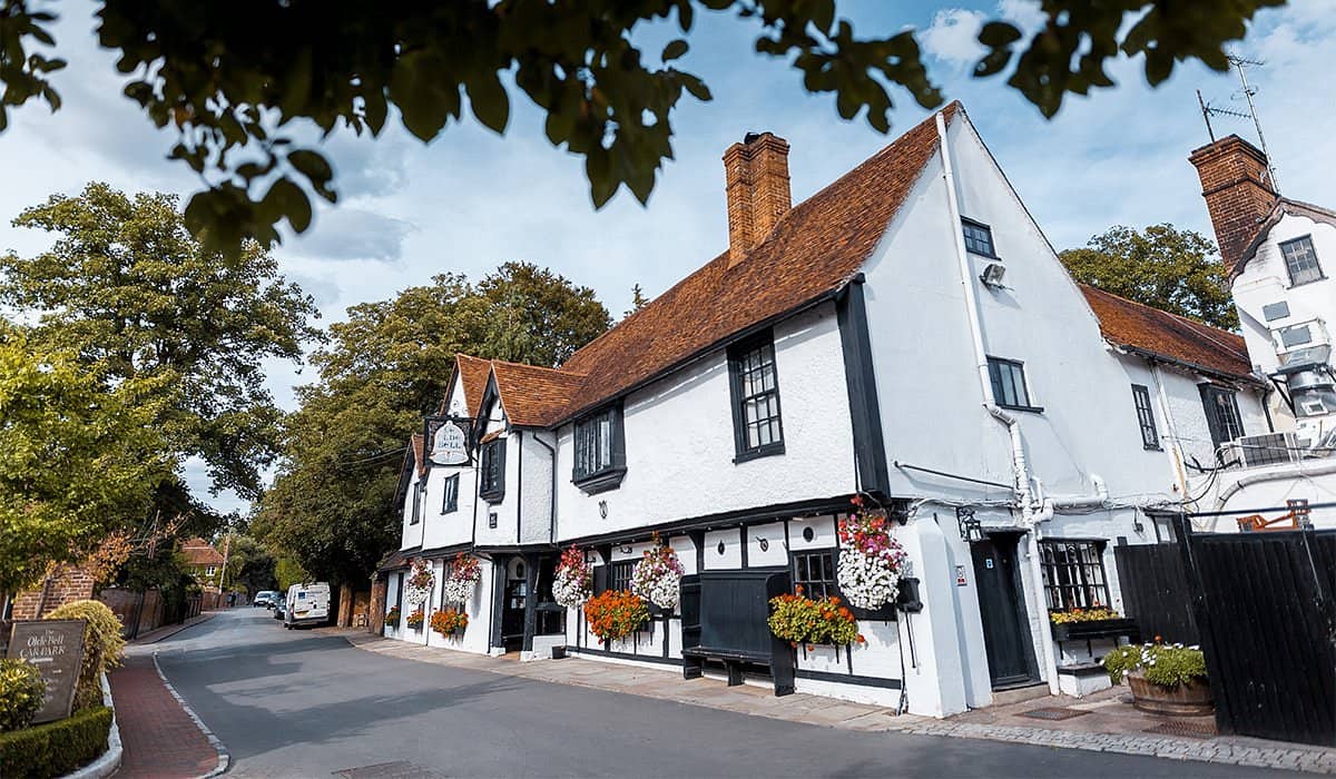 Exterior of the Olde Bell Hurley showing its black and white timber-framed facade with hanging baskets.
