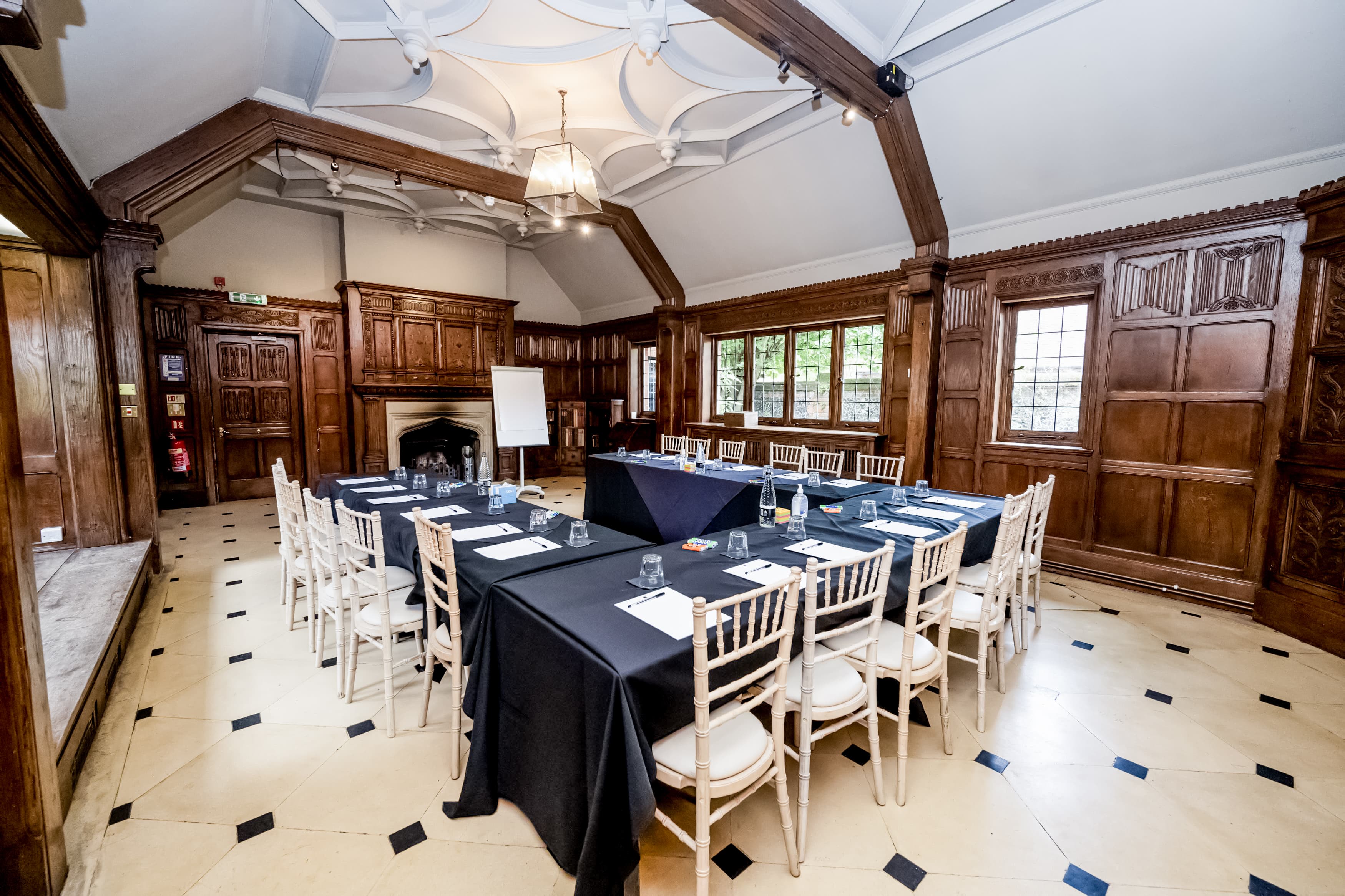 Panelled meeting room set with boardroom-style tables and white Chiavari chairs.