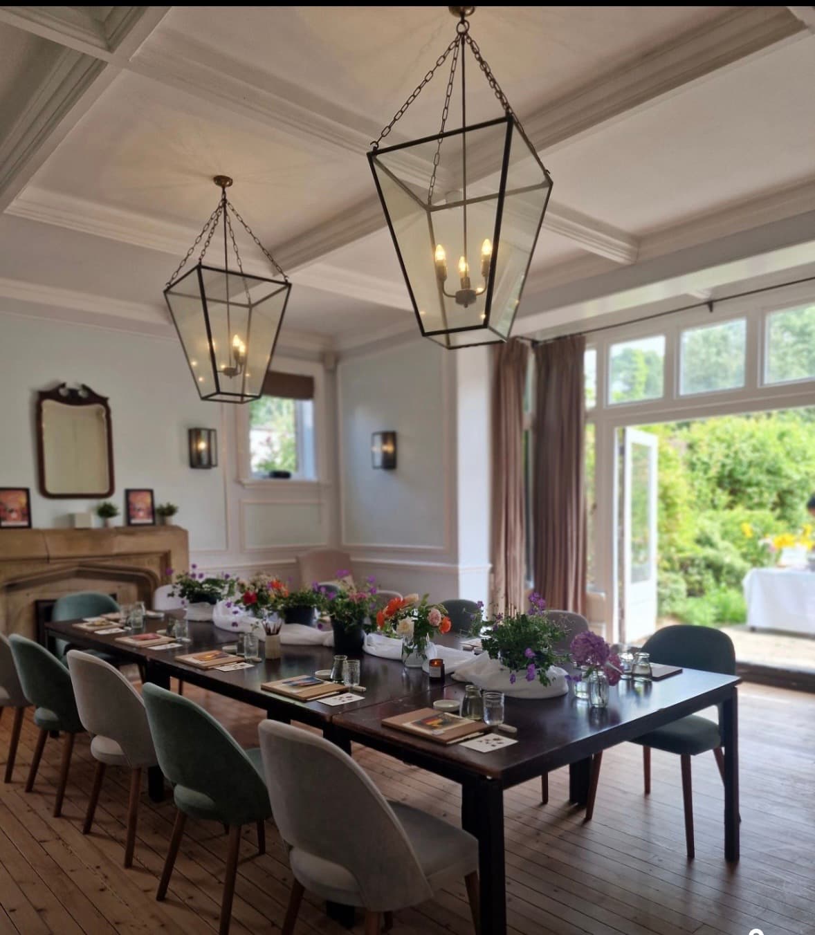 Private dining room with long dark table, floral displays and two lantern pendants.