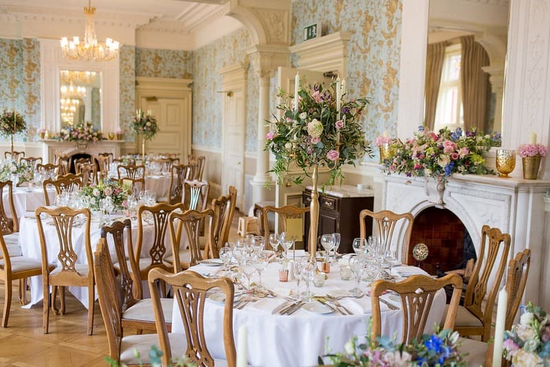 Pendley Manor Hotel's elegant function room dressed for a wedding breakfast with tall floral centrepieces.