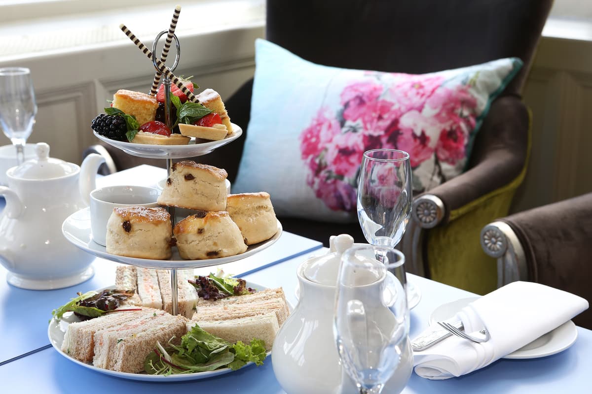 Afternoon tea spread with sandwiches, scones and cakes on a three-tier stand at Pendley Manor Hotel.