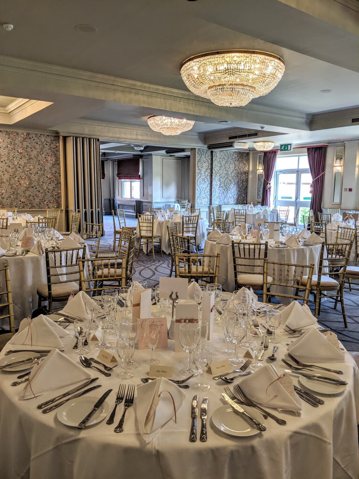 Pendley Manor Hotel function room laid for a formal dinner with crystal chandeliers overhead.