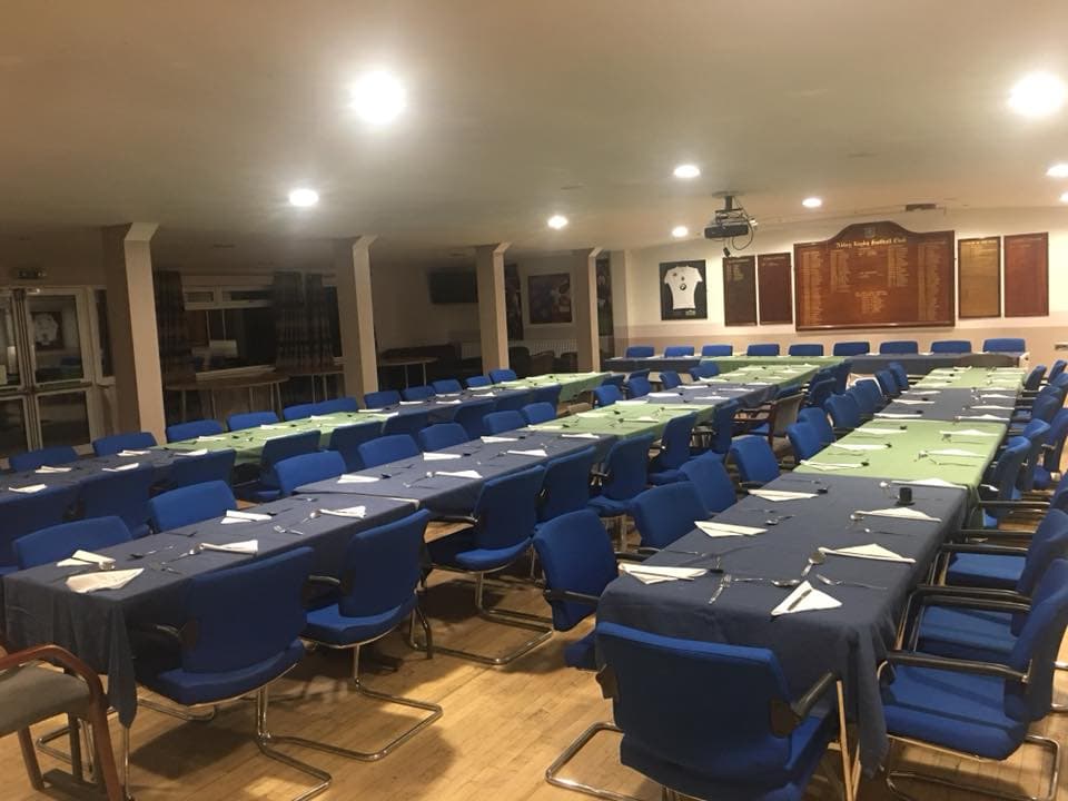 Function room laid with long tables, blue chairs and white napkins at Reading Abbey RFC.