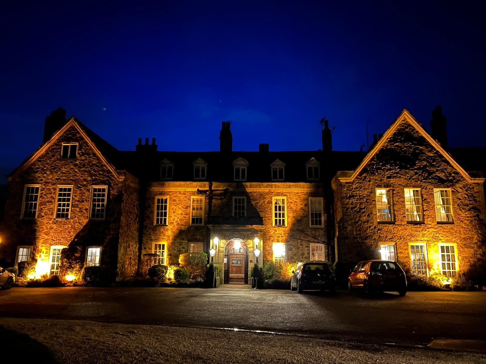 Rothley Court Hotel exterior at night, illuminated stonework and lit entrance doorway visible.