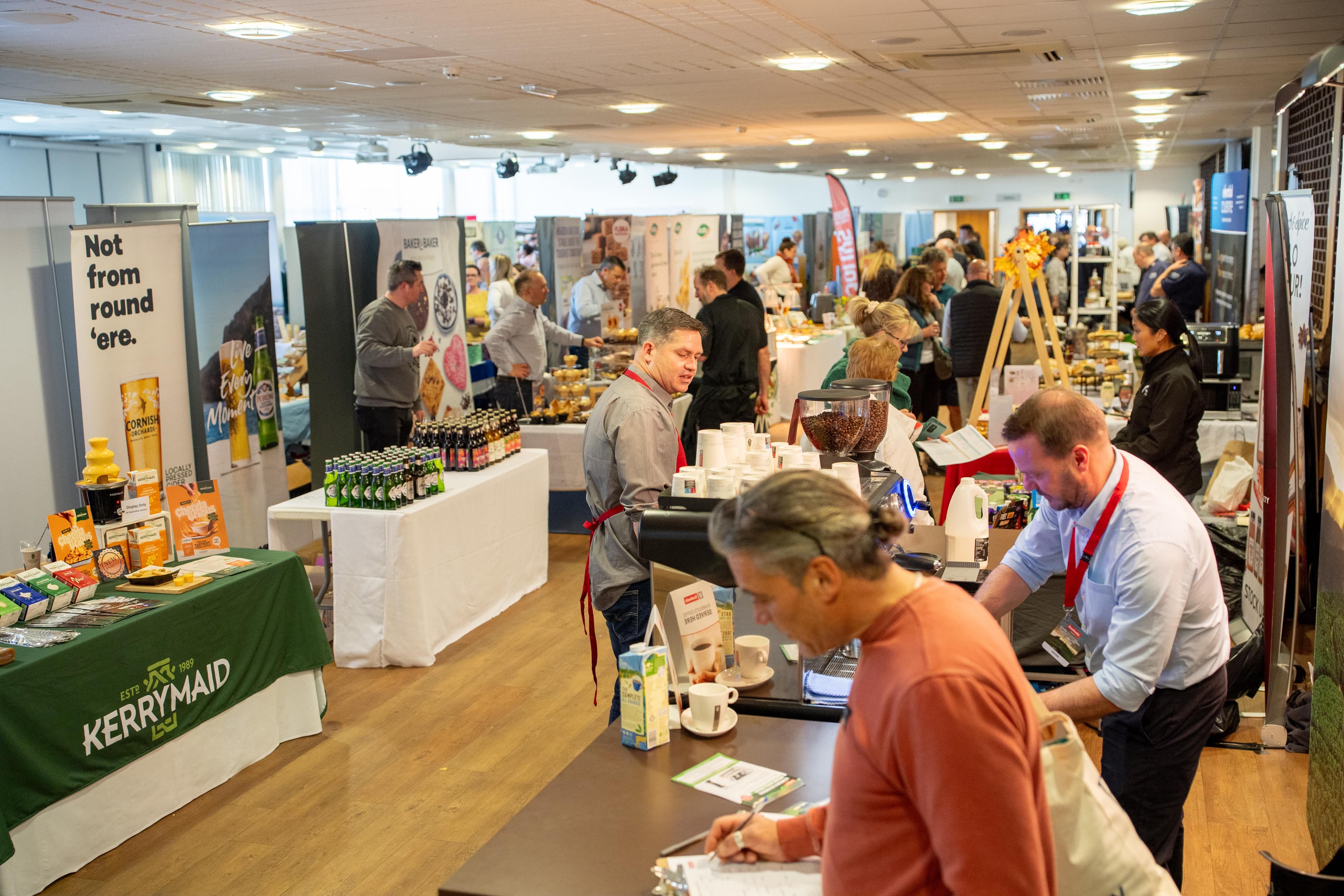 Tradeshow - Exhibitors and visitors browse food and drink trade stands inside a conference hall.