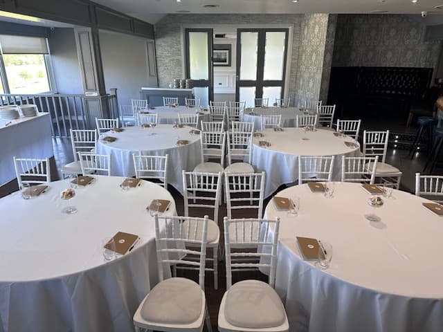 Function room set with round tables, white linen and white chiavari chairs.