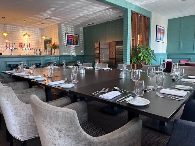 Private dining room laid for a group with dark tables and upholstered grey chairs