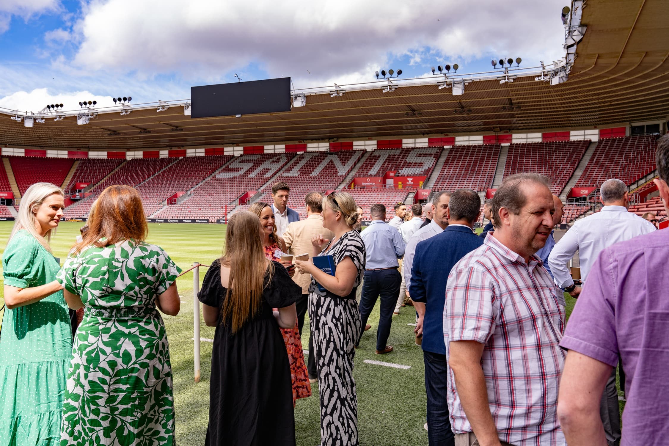 Guests mingling on the pitch at St Mary's Stadium on a sunny day.