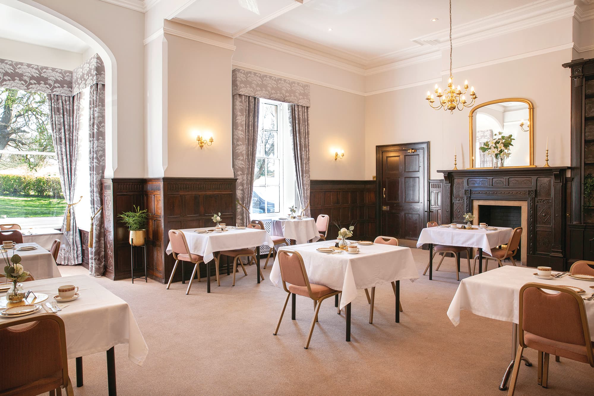 Strelley Hall dining room with white-clothed tables, ornate fireplace and garden views.