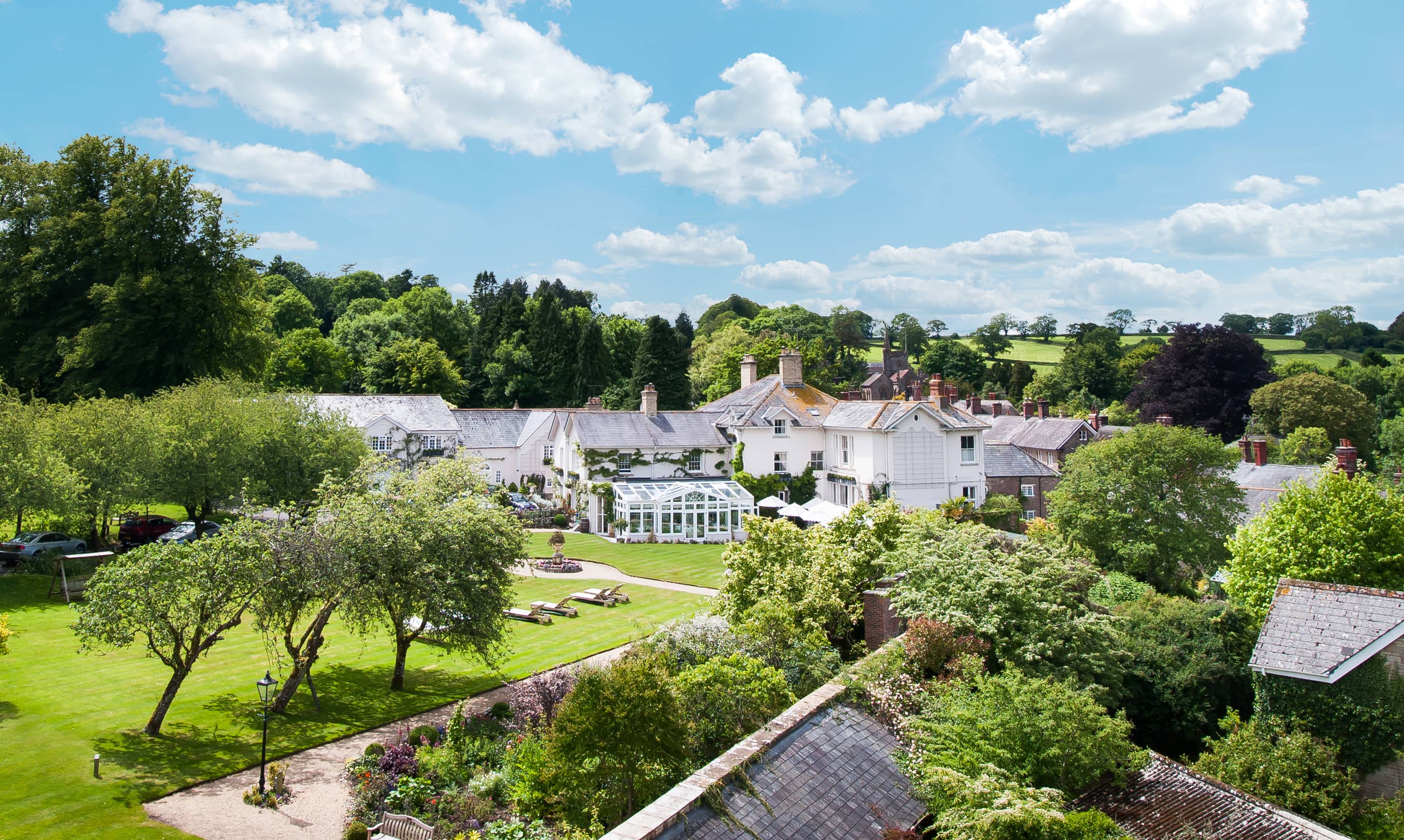 Aerial view of Summer Lodge Hotel's white country house exterior and manicured gardens.