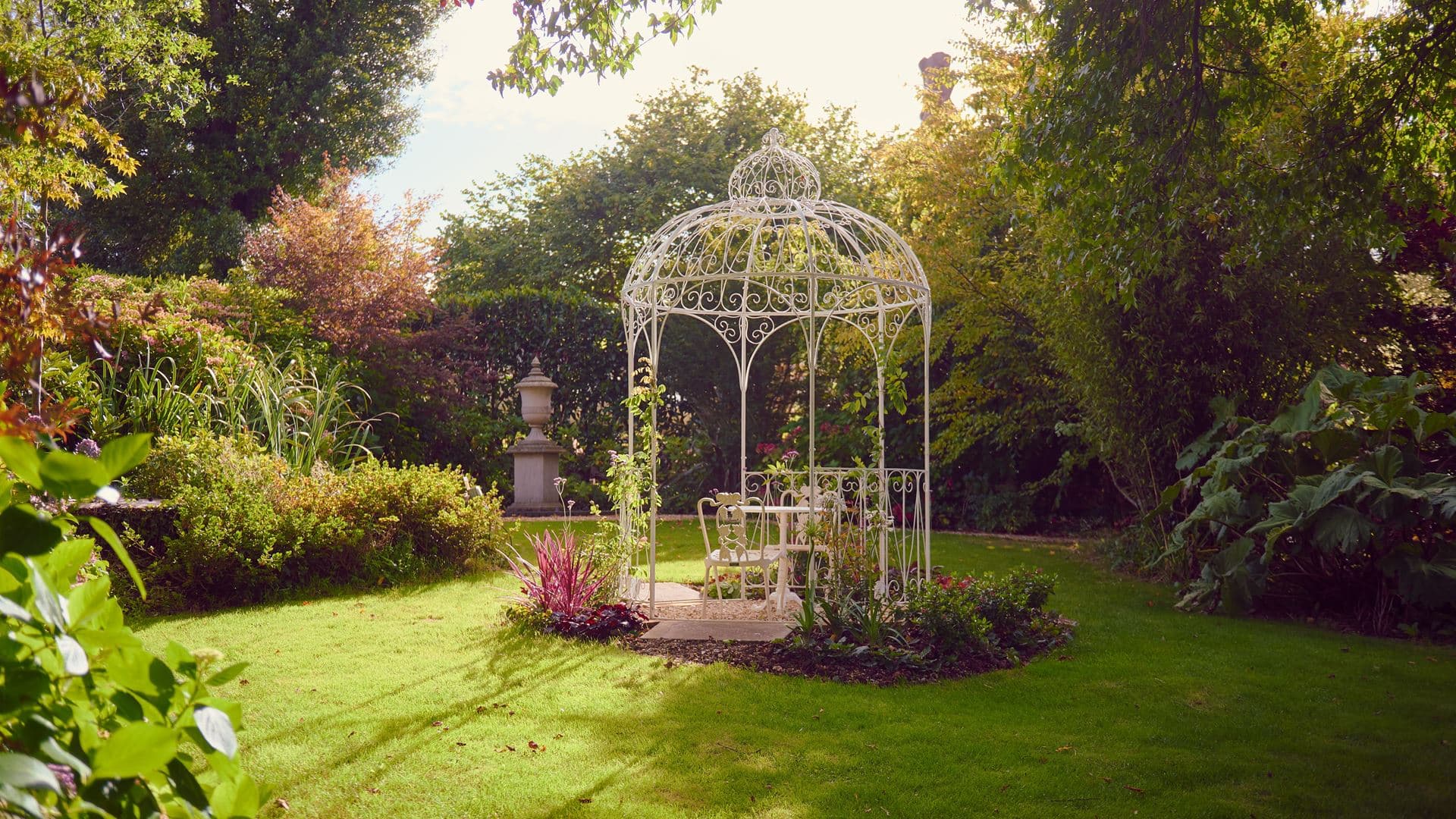 White wrought iron gazebo with garden furniture set in landscaped grounds at Summer Lodge Hotel.