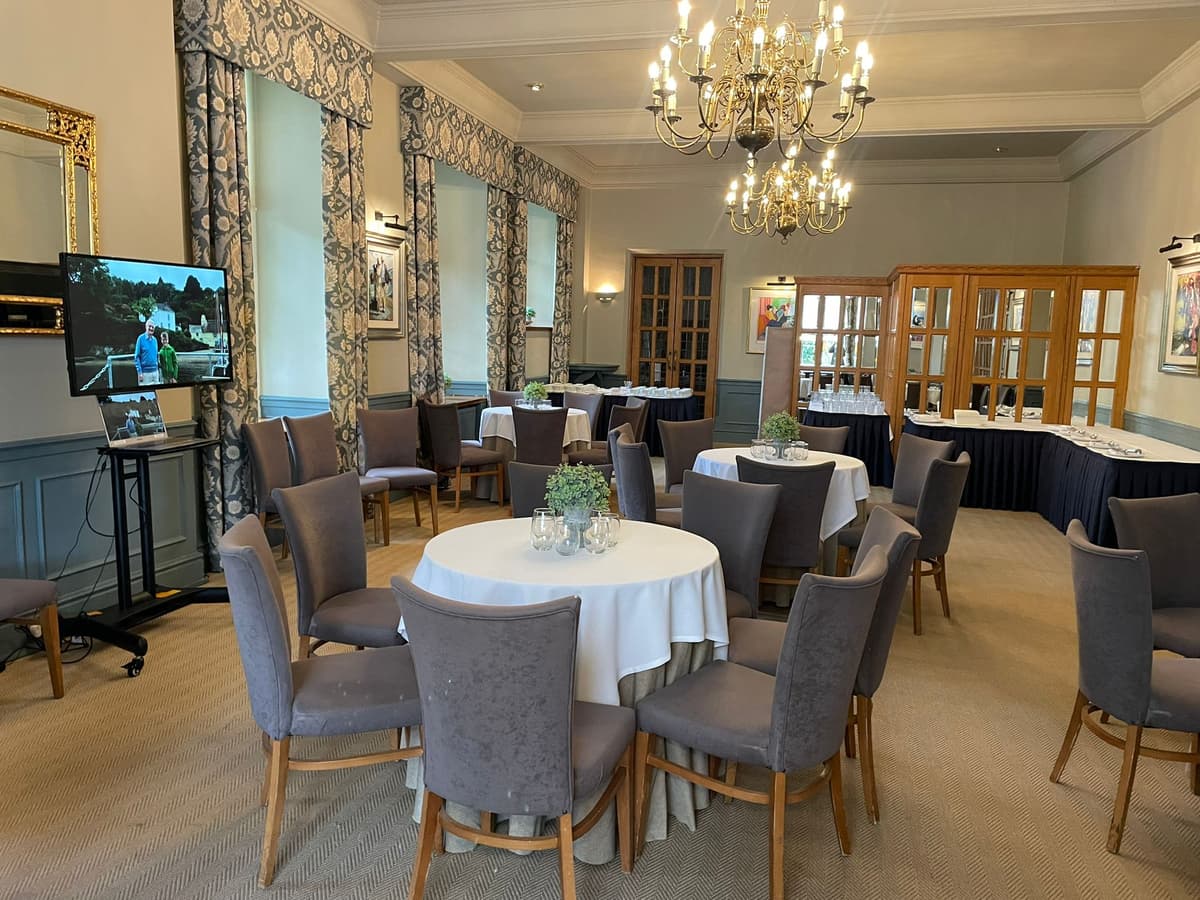 Elegantly dressed function room with round tables, chandelier and patterned curtains at The Castle Hotel Taunton.