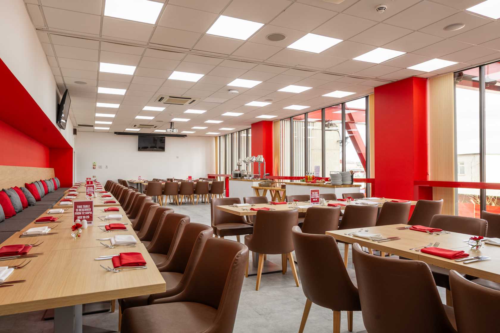 Bright hospitality dining room with red decor, laid tables and buffet station.