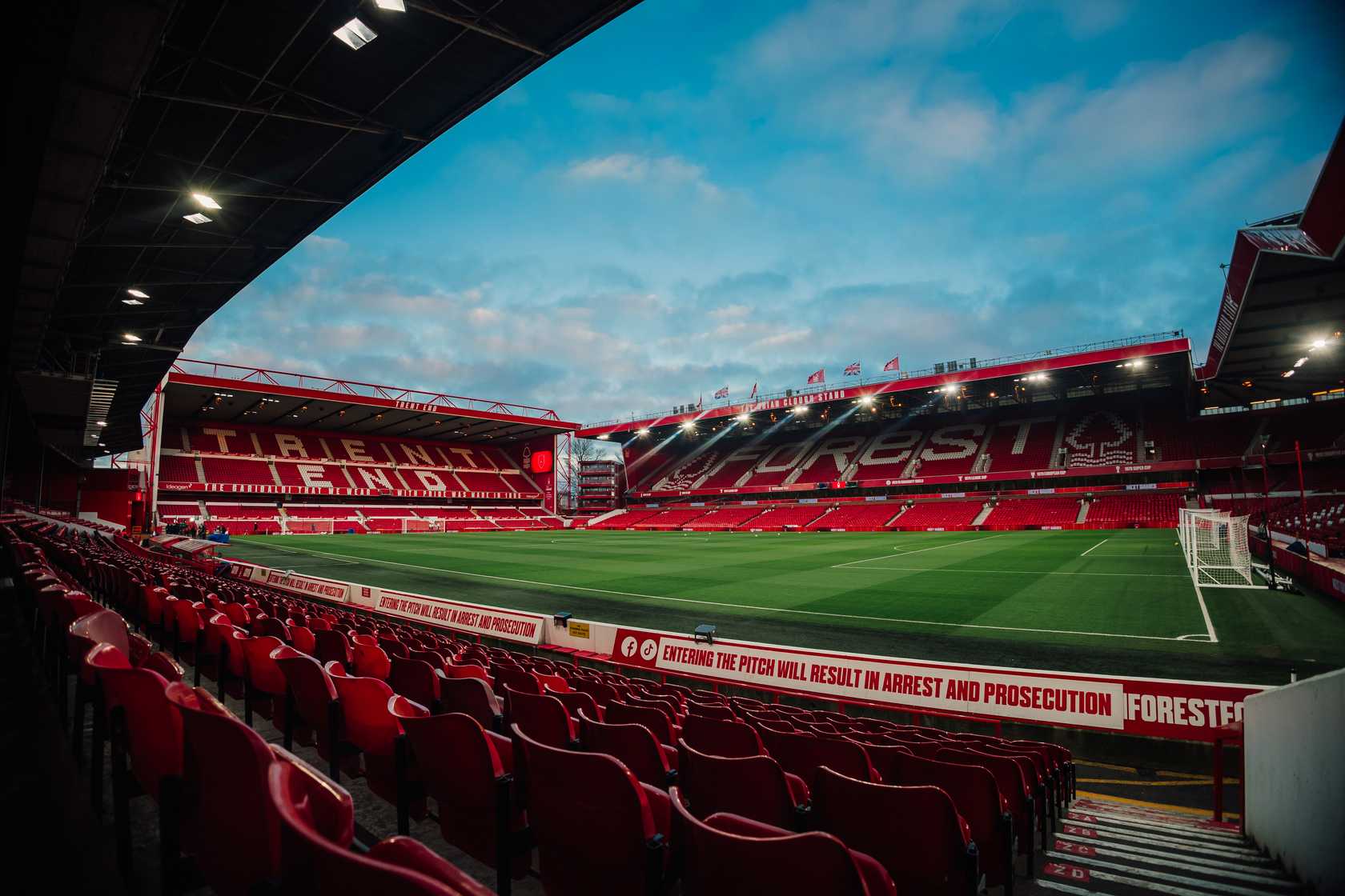 Empty red seats and green pitch inside the City Ground stadium, Nottingham.