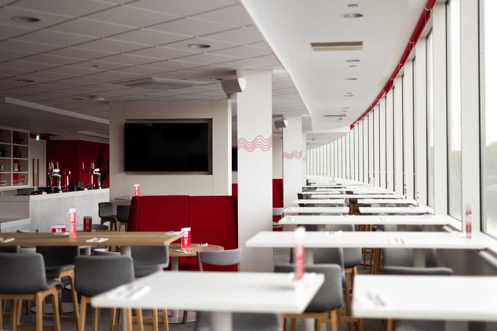 Bright hospitality suite with white tables, grey chairs and a bar area at The City Ground.
