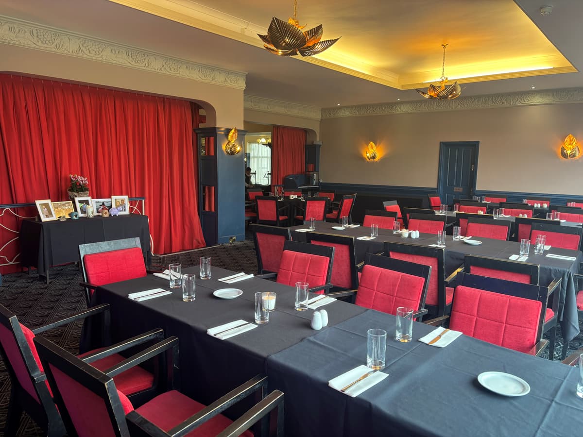 Function room at The Cumberland Hotel with red chairs and dark tablecloths set for dining.