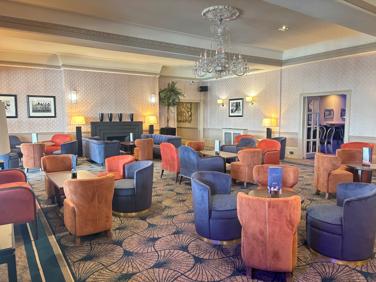 Lounge area at The Cumberland Hotel with velvet armchairs and a crystal chandelier.