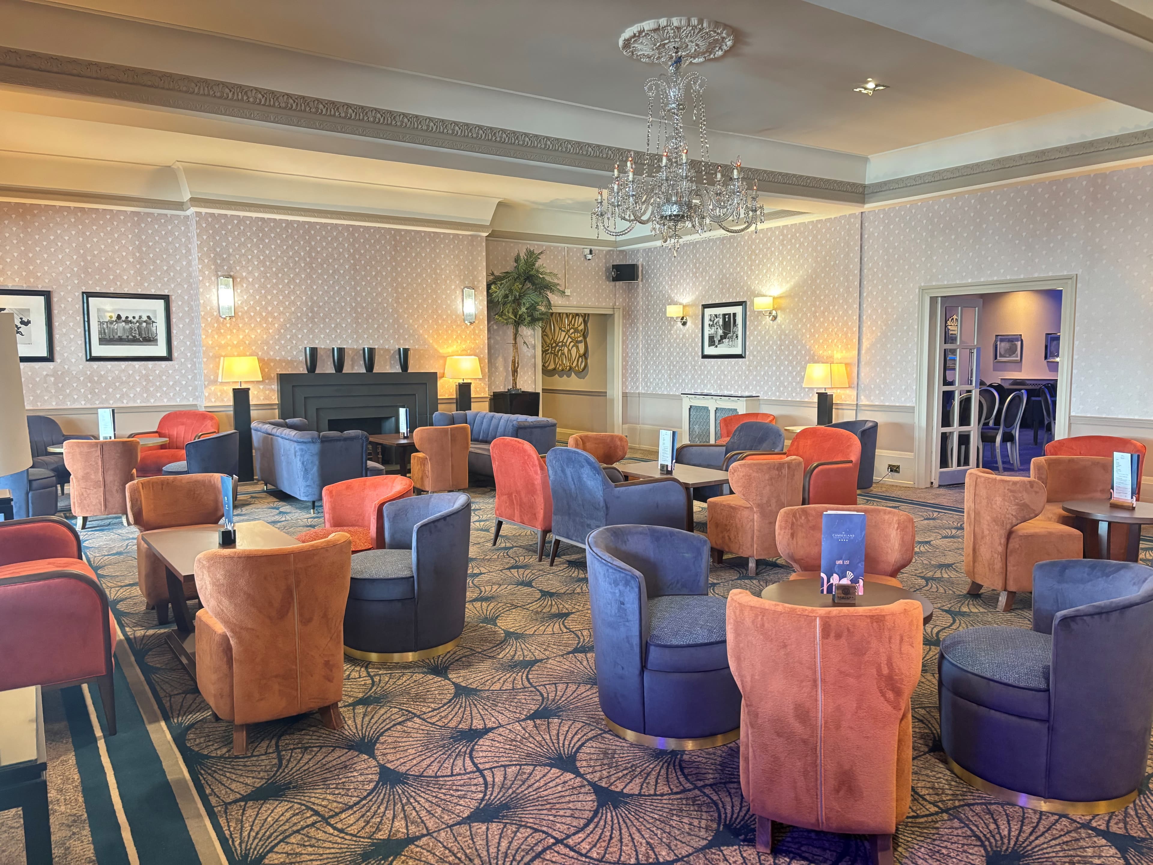 Lounge area at The Cumberland Hotel with velvet armchairs and a crystal chandelier.