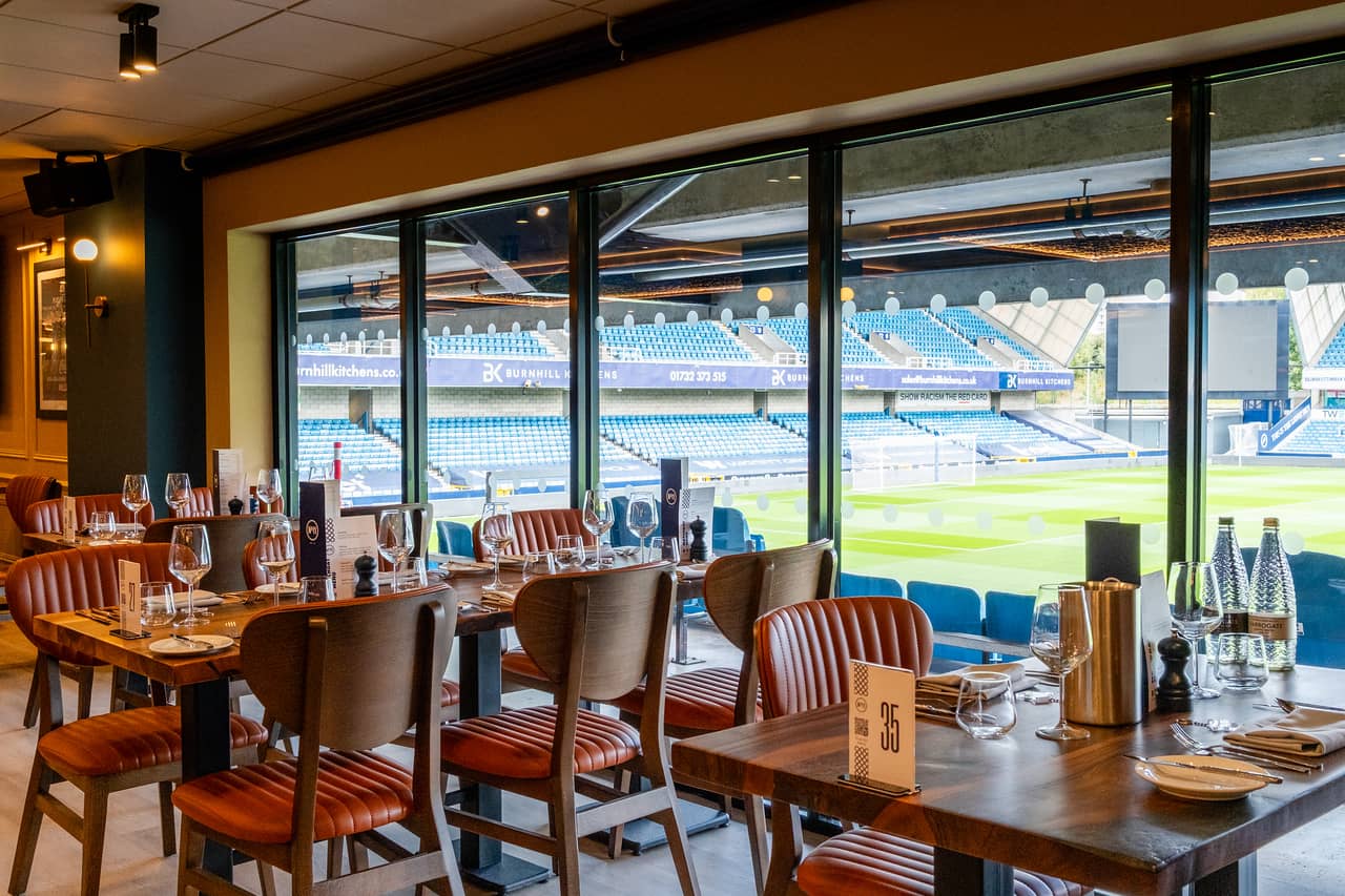 Dining room with leather chairs and pitch views through large floor-to-ceiling windows at The Den.