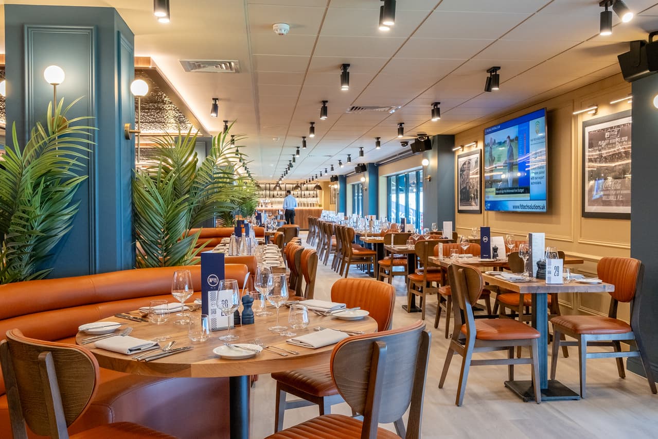Smartly laid dining room with tan leather seating, tropical plants and framed football memorabilia.