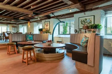 Rustic lounge area with curved booth seating, round wooden table and exposed ceiling beams.
