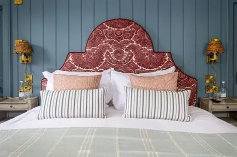 Double bed with a red paisley headboard against blue-grey panelled walls at The Egypt Mill.