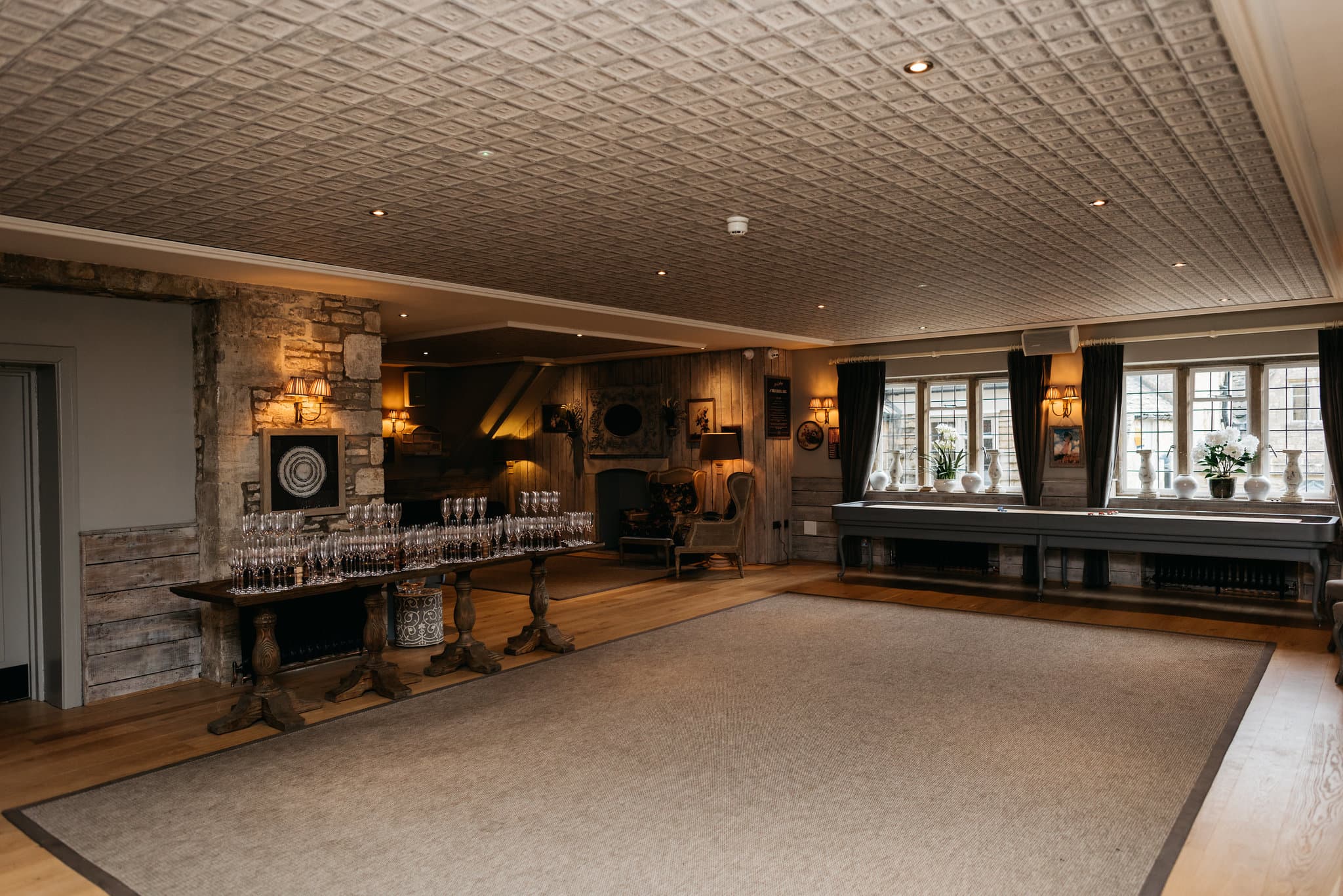 Spacious function room at The Frogmill with champagne glasses, shuffleboard and stone fireplace.
