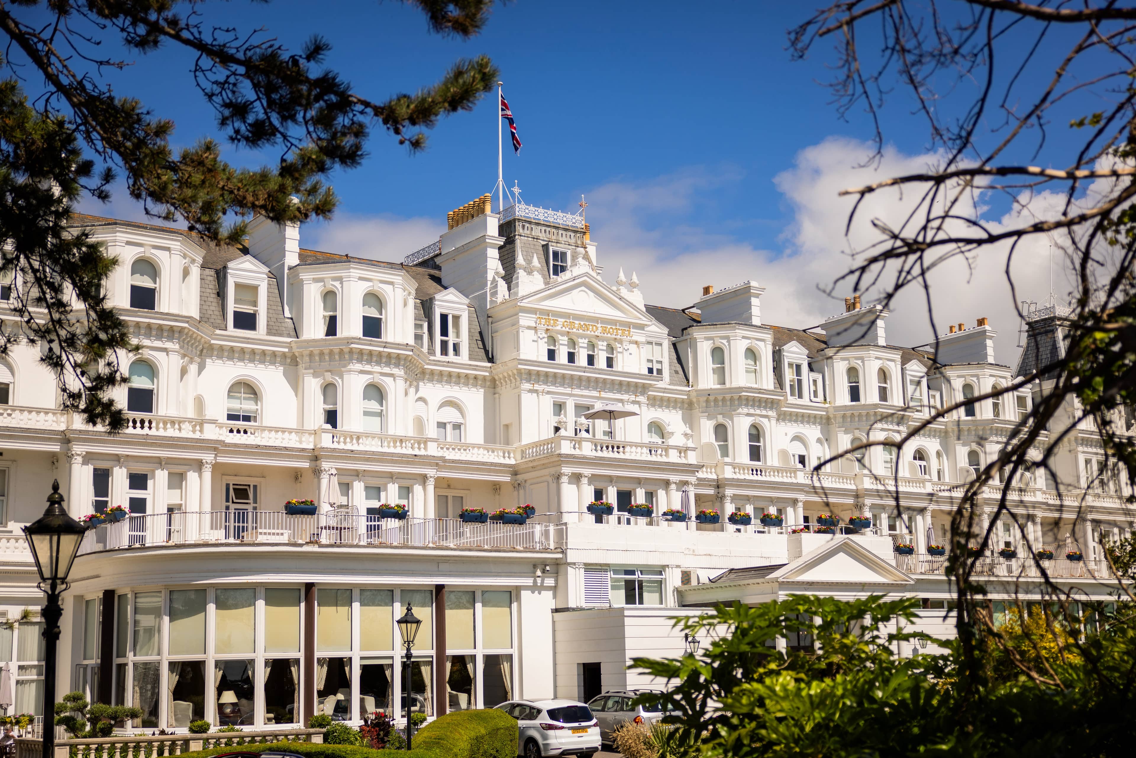 The white Victorian facade of The Grand Hotel Eastbourne with a Union Jack flying above.