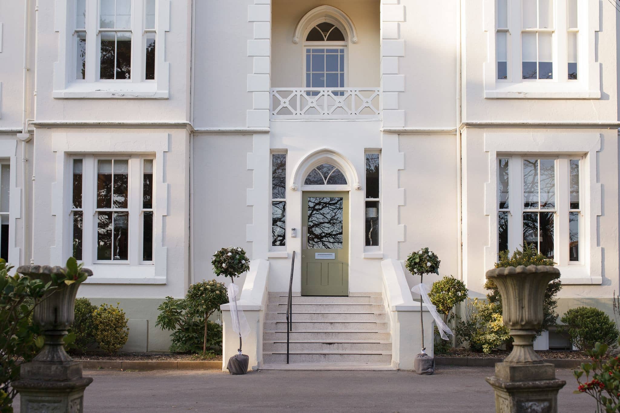 The white rendered exterior of The Green House Hotel with a sage green front door.