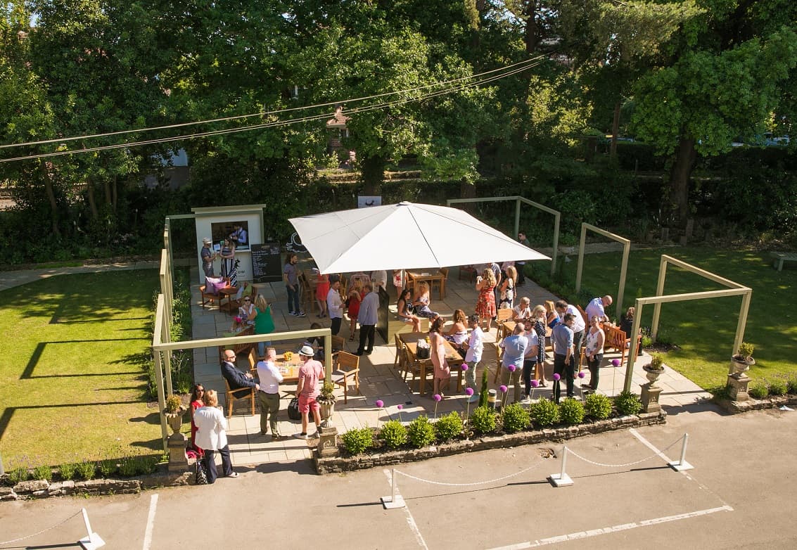Guests gather on a sunny hotel terrace beneath a large white parasol in Bournemouth.