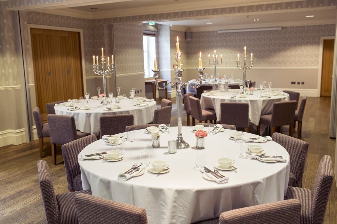 Private dining room with round tables, silver candelabras and mauve upholstered chairs.