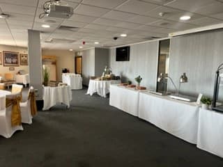 Function room laid out with white-clothed tables and a buffet serving station.