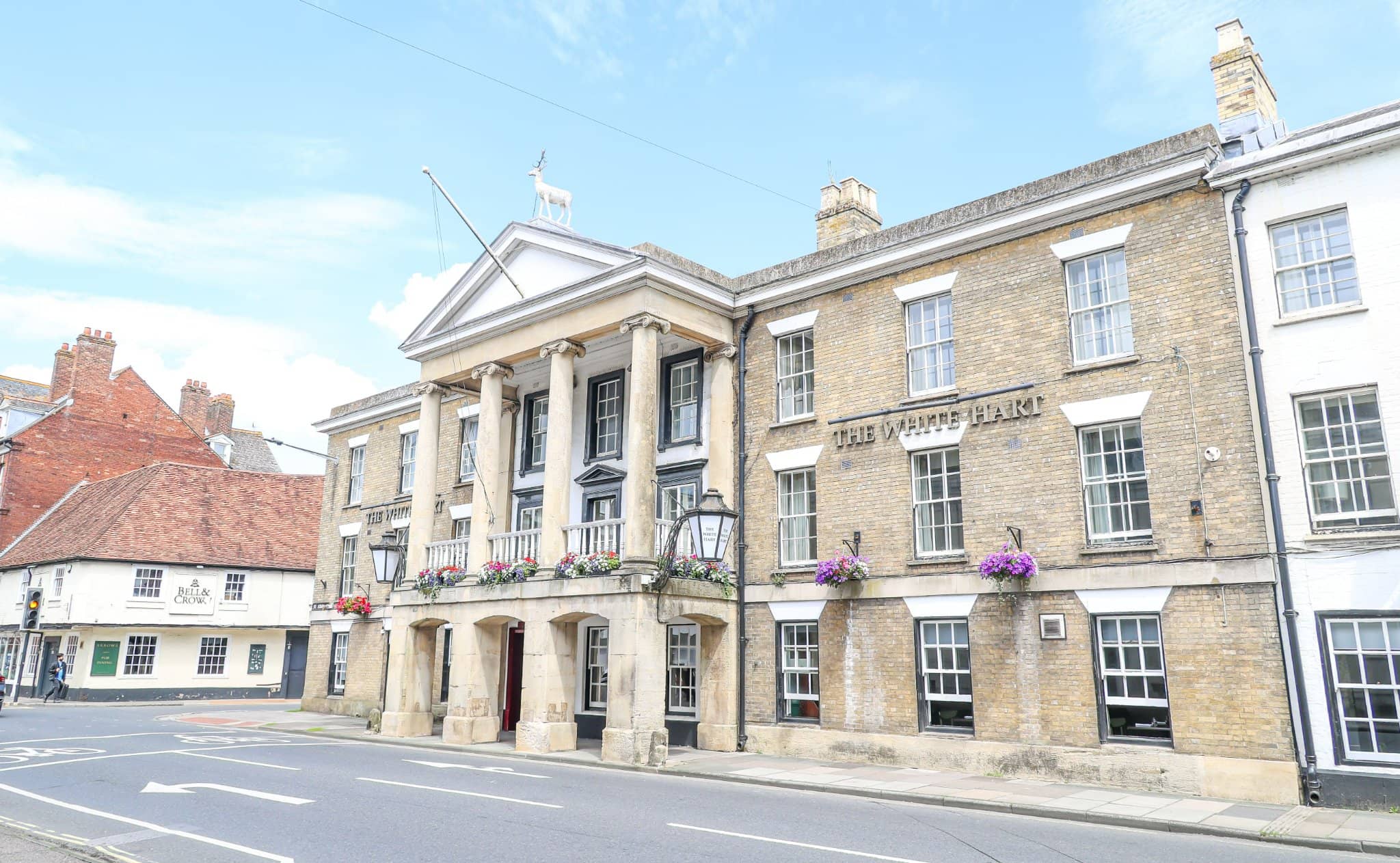 Exterior of The White Hart Hotel showing its Georgian facade and white stag statue.