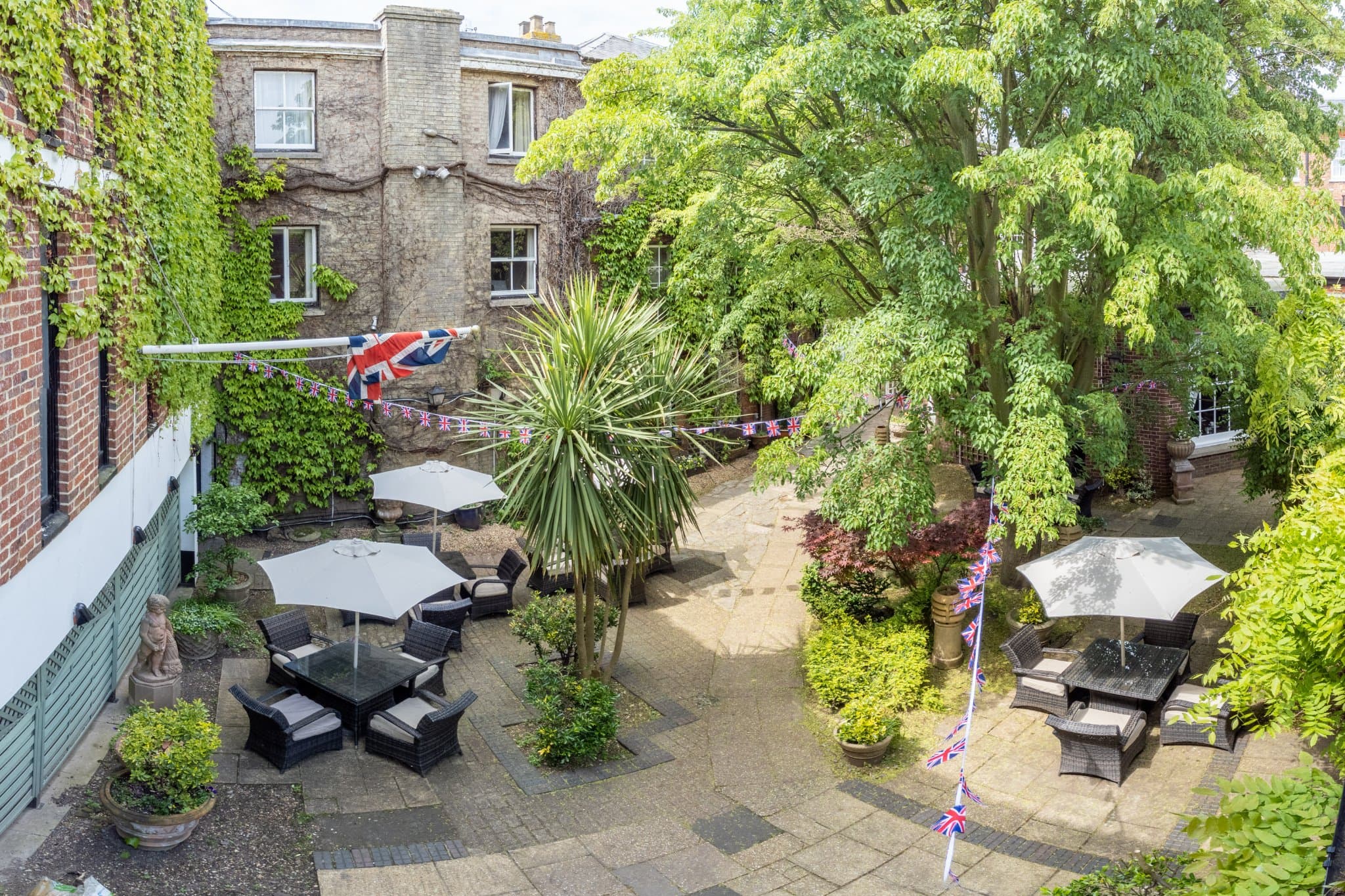 Courtyard garden with rattan seating, parasols and Union Jack bunting at Mercure White Hart Hotel.
