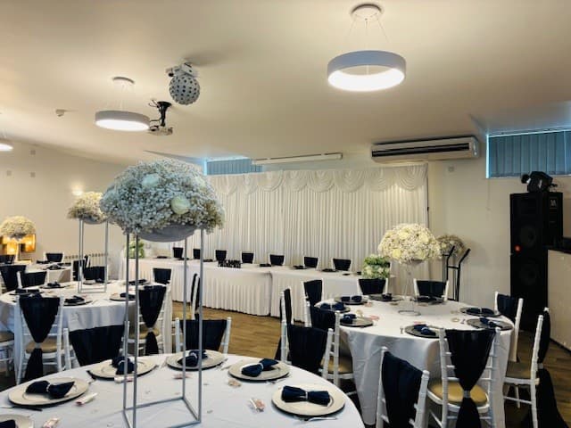 Function room laid for an event with round tables, navy napkins and tall floral centrepieces.