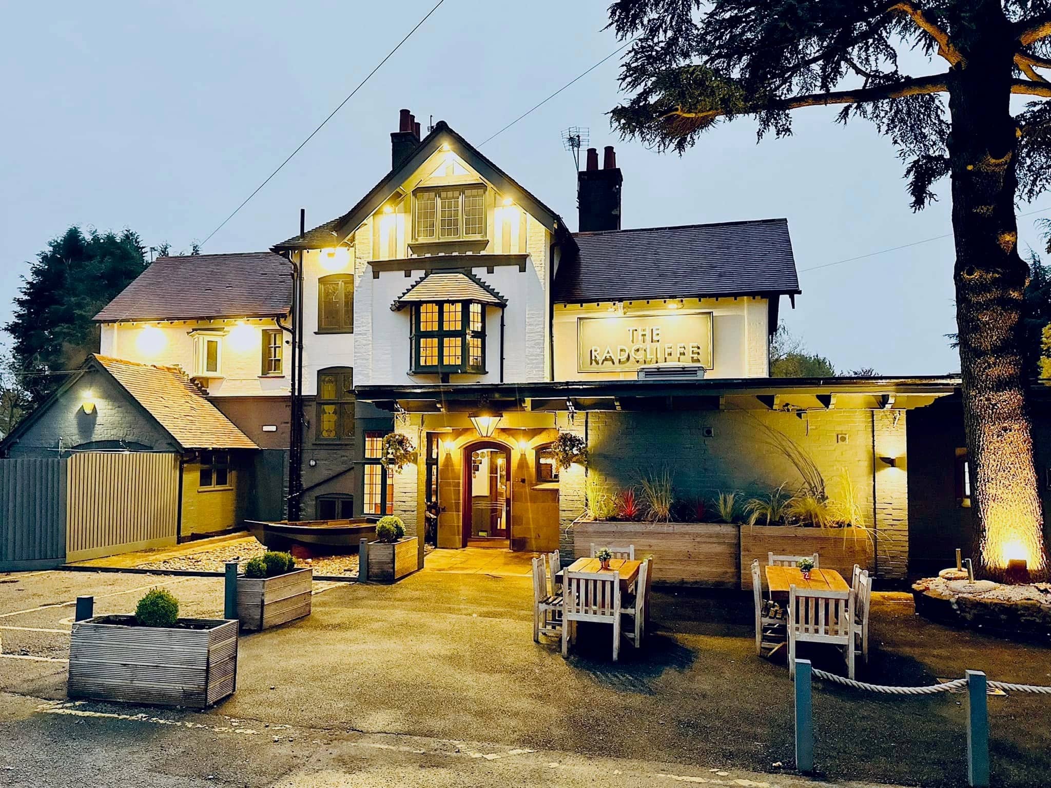 The Radcliffe pub exterior at dusk with outdoor seating and warm lighting.