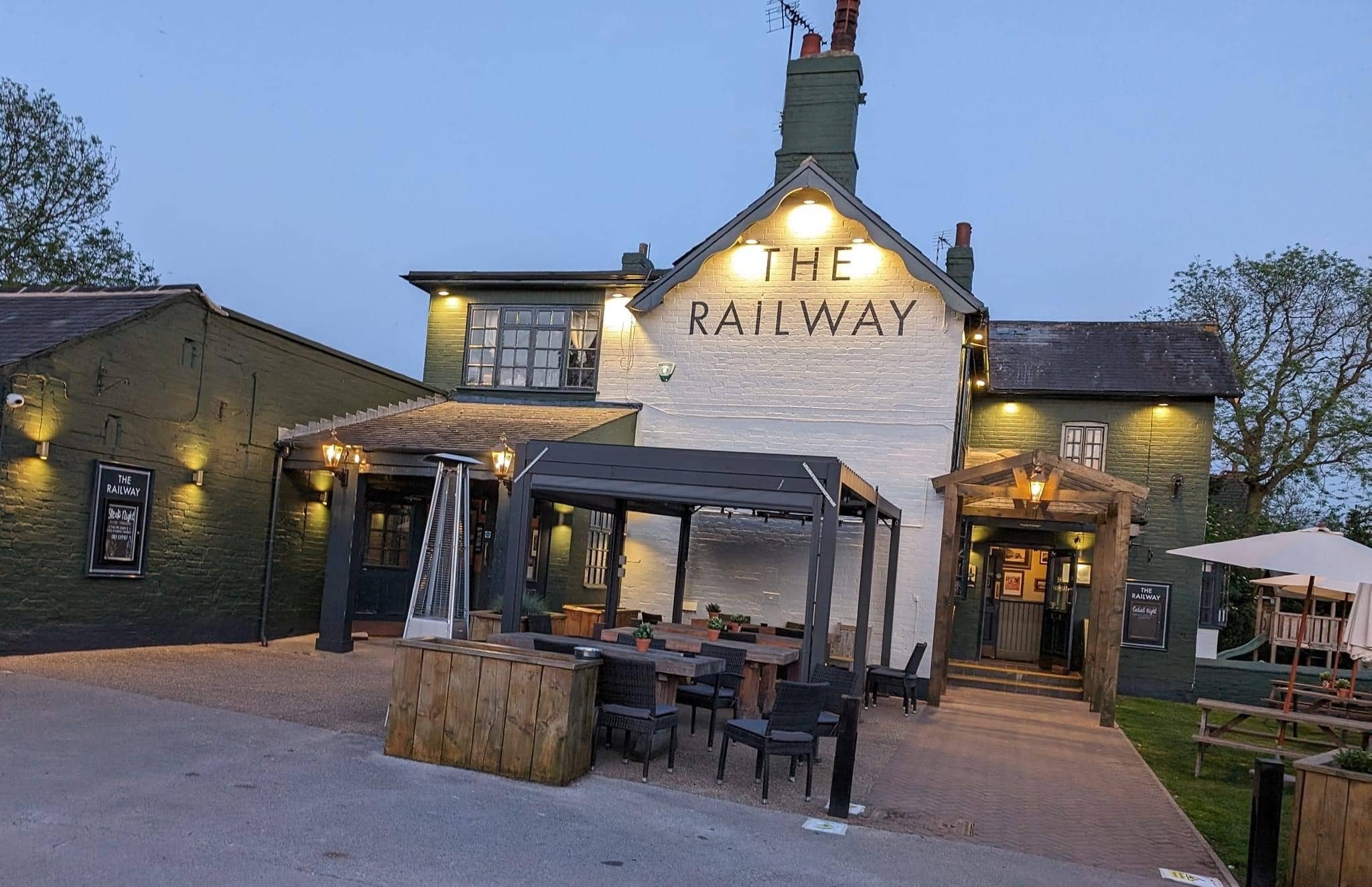 The exterior of The Railway pub in Nottingham at dusk with outdoor seating.