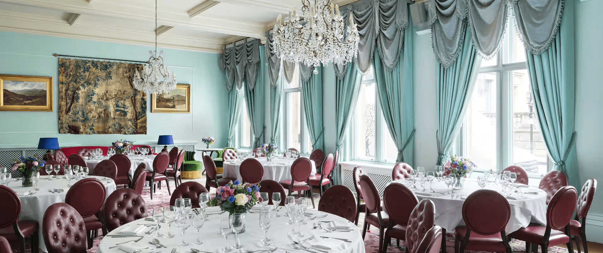 Elegant dining room at The Randolph Hotel with round tables, crystal chandeliers and duck-egg blue walls.