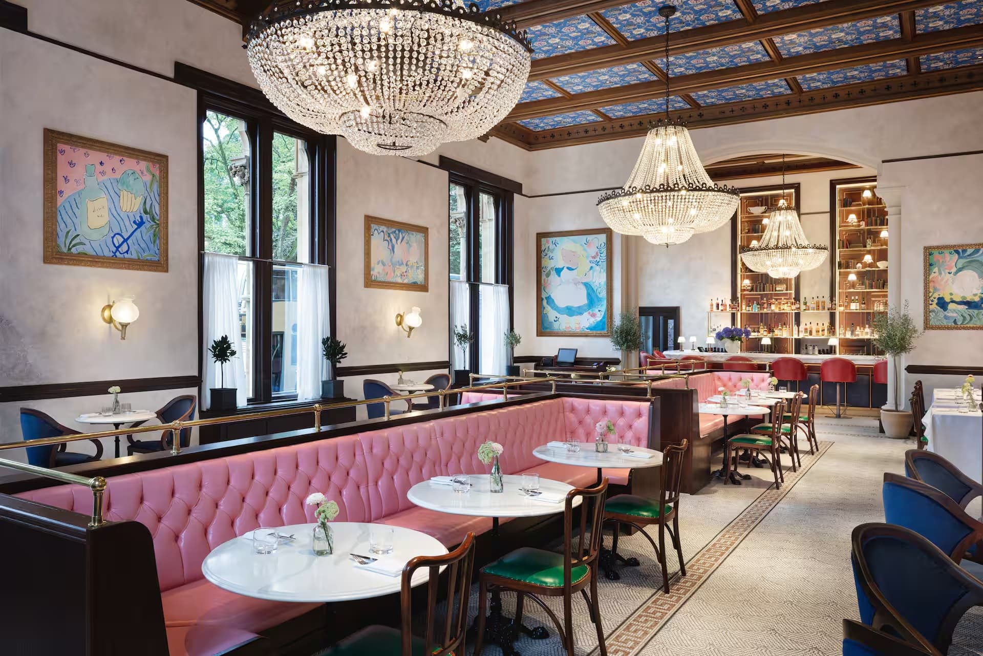 The Randolph Hotel dining room with pink banquettes, crystal chandeliers and colourful artwork.