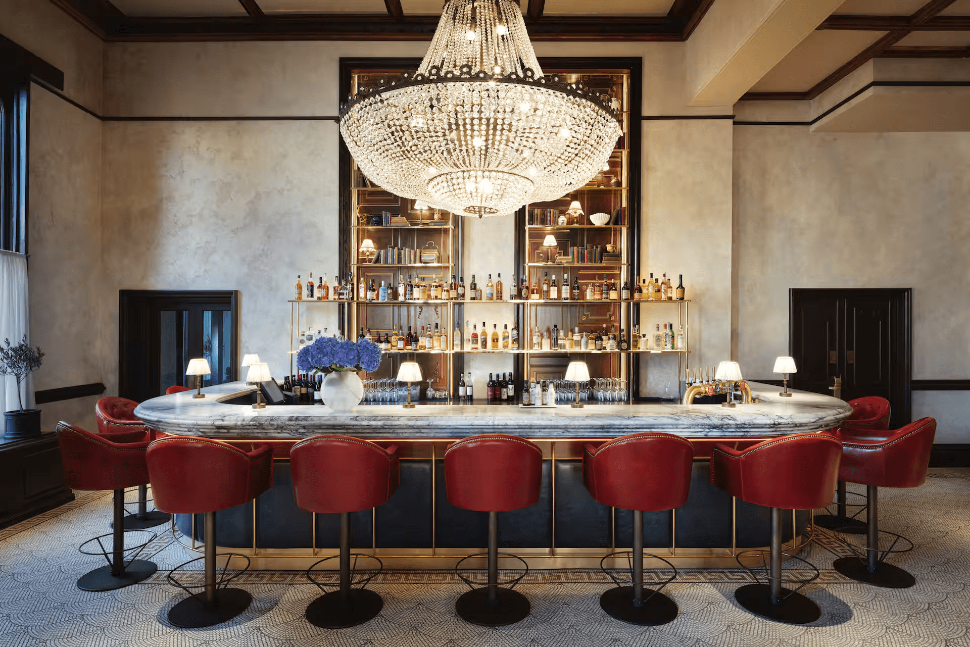 The Randolph Hotel bar with marble counter, red leather stools and crystal chandelier.