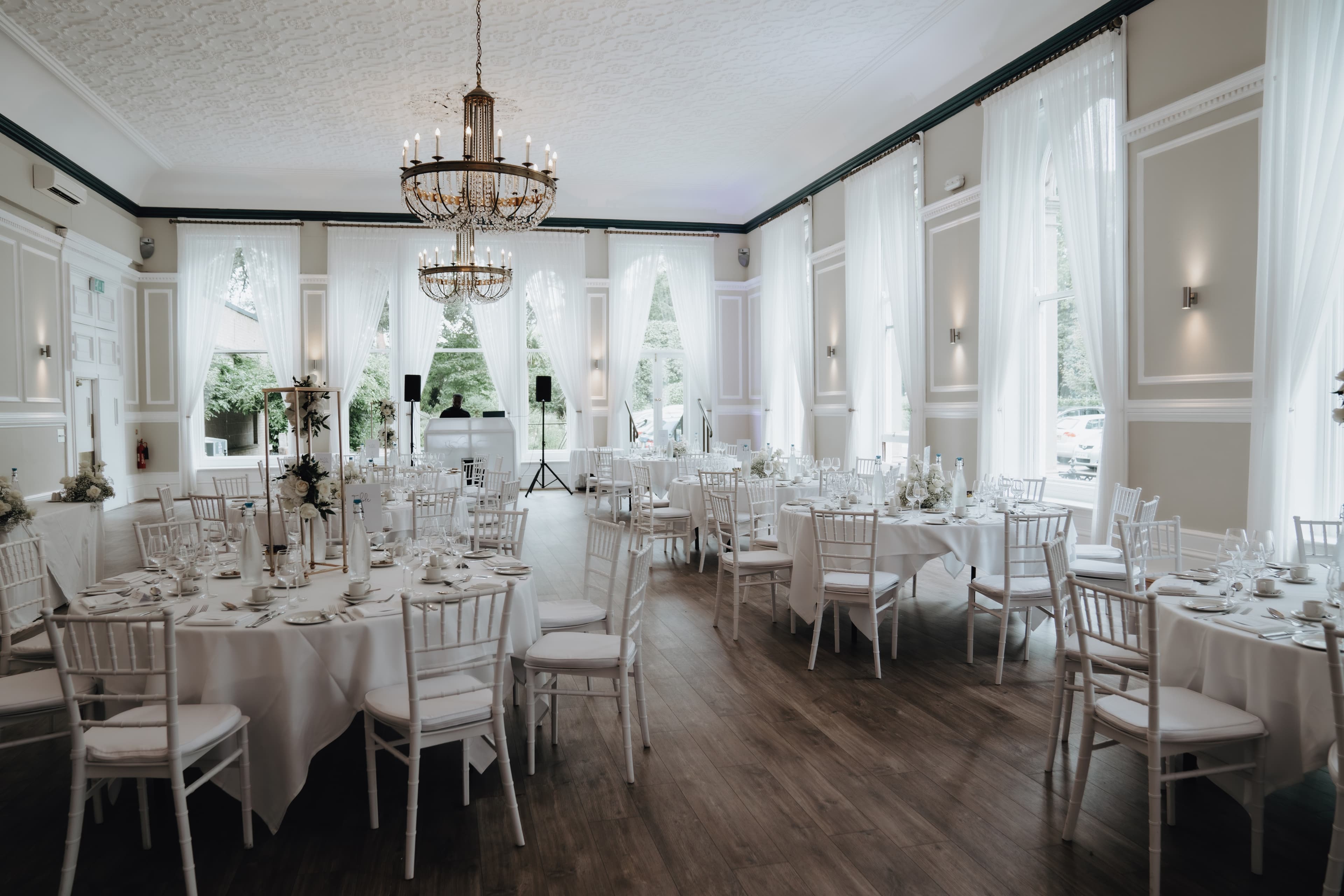 The Spa Hotel's function room laid for a formal dinner with white chiavari chairs and chandelier.